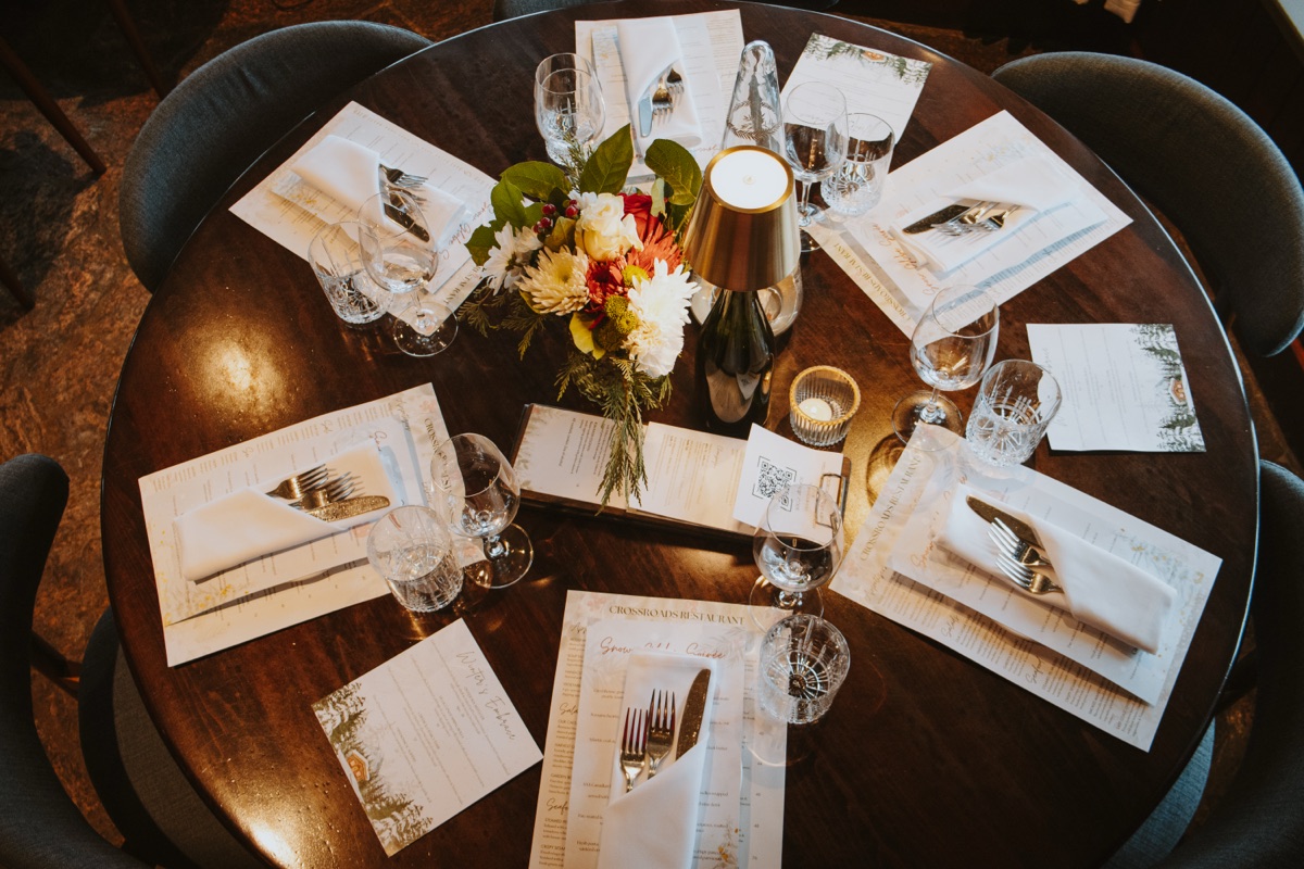 A round table set for a large group dinner at Crossroads, with menus and floral centerpiece